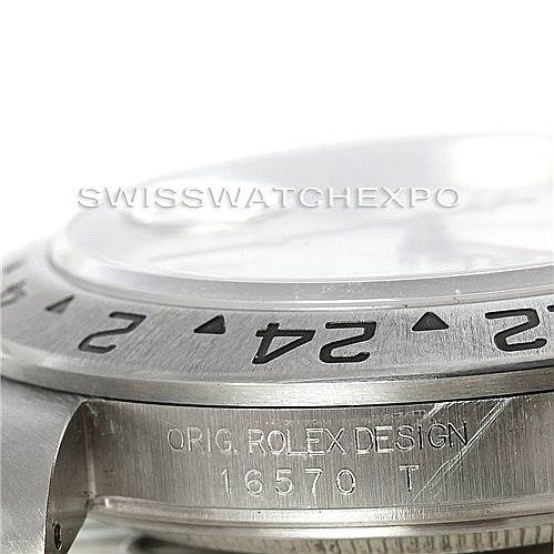 This image shows a close-up of the bezel and part of the case of the Rolex Explorer 16570 Men's Stainless Steel White Dial 16570 Men's Stainless Steel White Dial model, including engraved markings "ORIG. ROLEX DESIGN 16570 T".