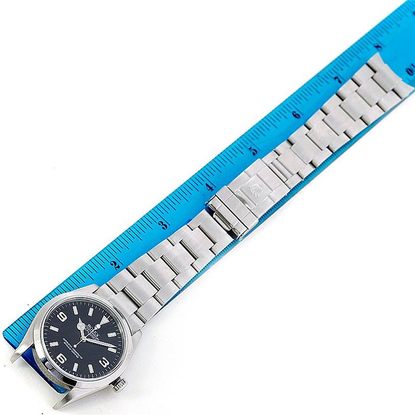 The image shows a top-down view of a Rolex Explorer 114270 Men's Stainless Steel Black Dial 114270 Men's Stainless Steel Black Dial watch laid beside a ruler measuring the length of its metal bracelet.