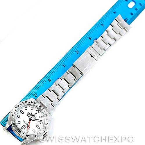 The Rolex Explorer 216570 Men's Stainless Steel White Dial 216570 Men's Stainless Steel White Dial watch is shown flat with its face and bracelet visible, placed next to a blue ruler for measurement.