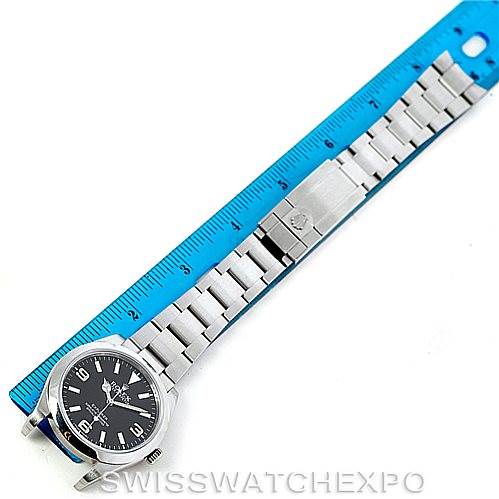 The Rolex Explorer 214270 Men's Stainless Steel Black Dial 214270 Men's Stainless Steel Black Dial watch is shown from a top-down angle, revealing the face, bracelet, and clasp next to a measuring ruler.