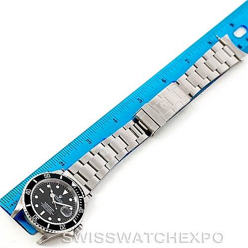 The image shows a Rolex Explorer 16570 Men
s Stainless Steel White Dial 16570 Men
s Stainless Steel White Dial watch laid flat next to a blue ruler, displaying the bracelet, clasp, and face of the watch from an overhead angle.