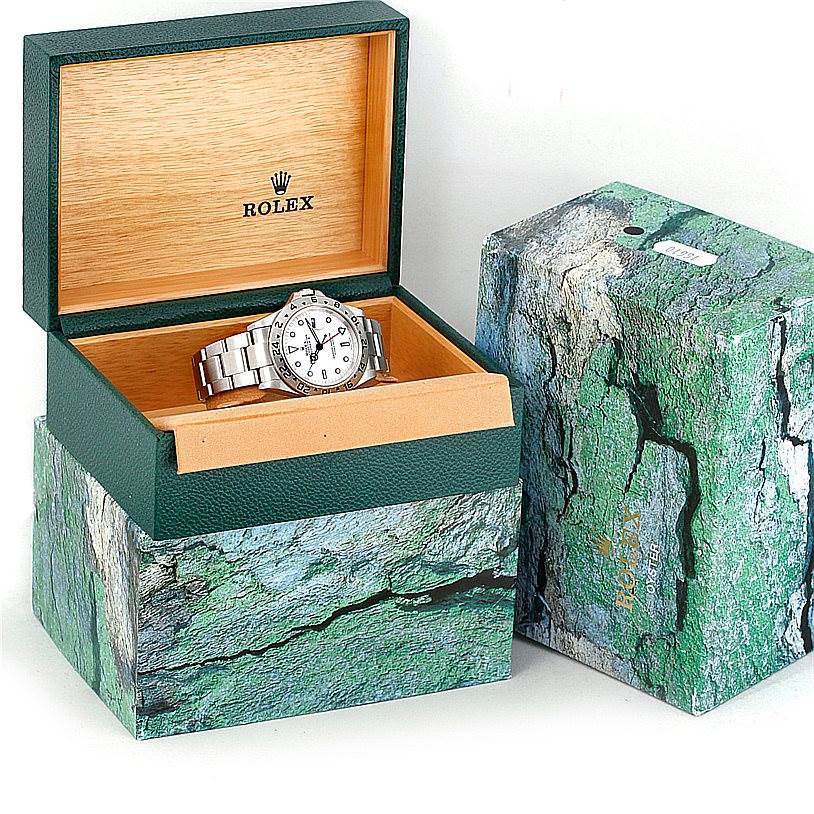 The Rolex Explorer 16570 Men's Stainless Steel White Dial 16570 Men's Stainless Steel White Dial watch is displayed inside an open green and wood box, centered in the frame with closed packaging beside it.
