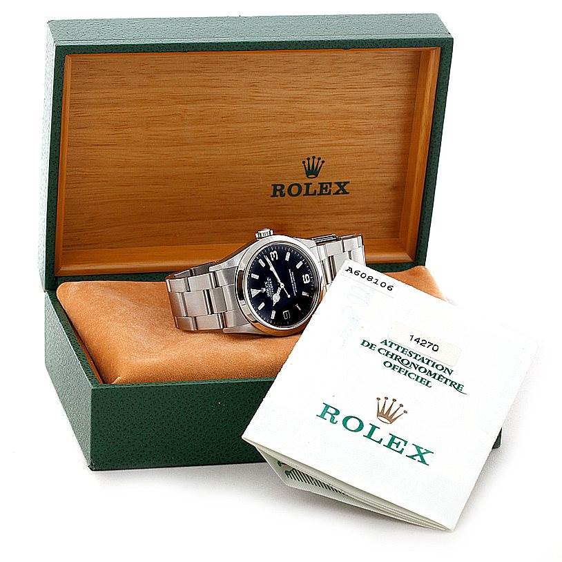 The image shows a Rolex Explorer 14270 Men's Stainless Steel Black Dial 14270 Men's Stainless Steel Black Dial watch in its open box, accompanied by warranty papers.