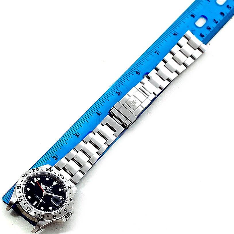 The image shows a Rolex Explorer 16570 Men's Stainless Steel Black Dial 16570 Men's Stainless Steel Black Dial watch laying flat next to a ruler, highlighting its bracelet and clasp.