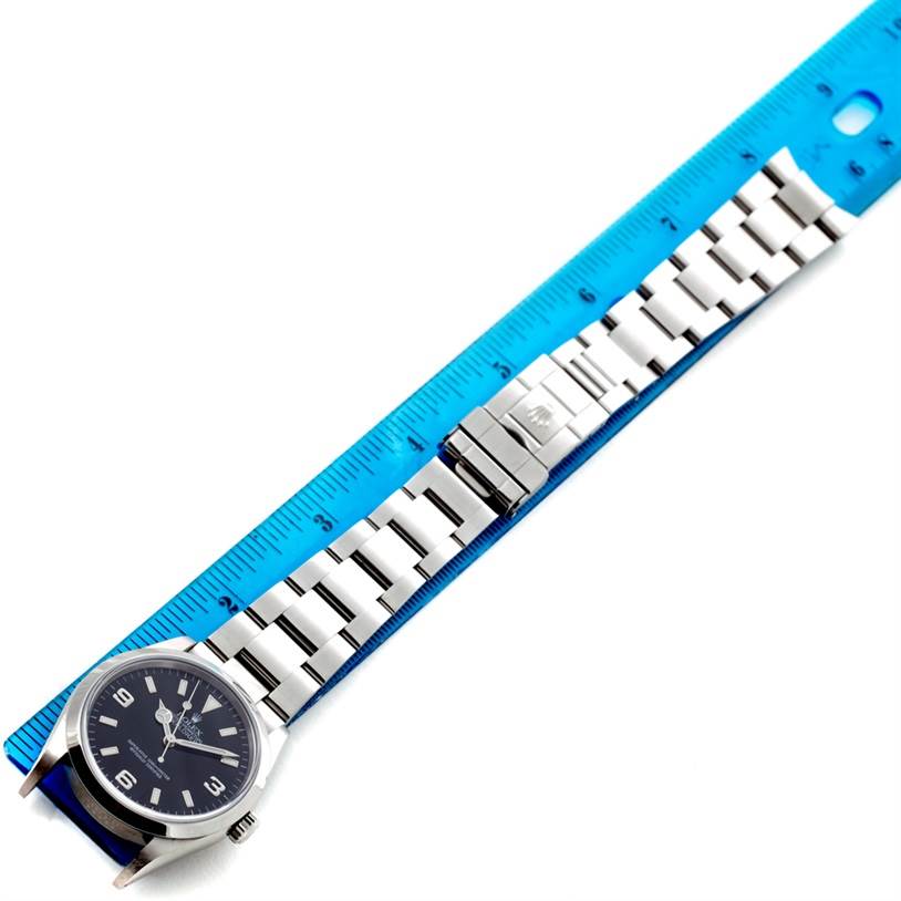 The image shows a Rolex Explorer 114270 Men's Stainless Steel Black Dial 114270 Men's Stainless Steel Black Dial watch laid flat next to a blue ruler, highlighting the watch face, bracelet, and clasp.