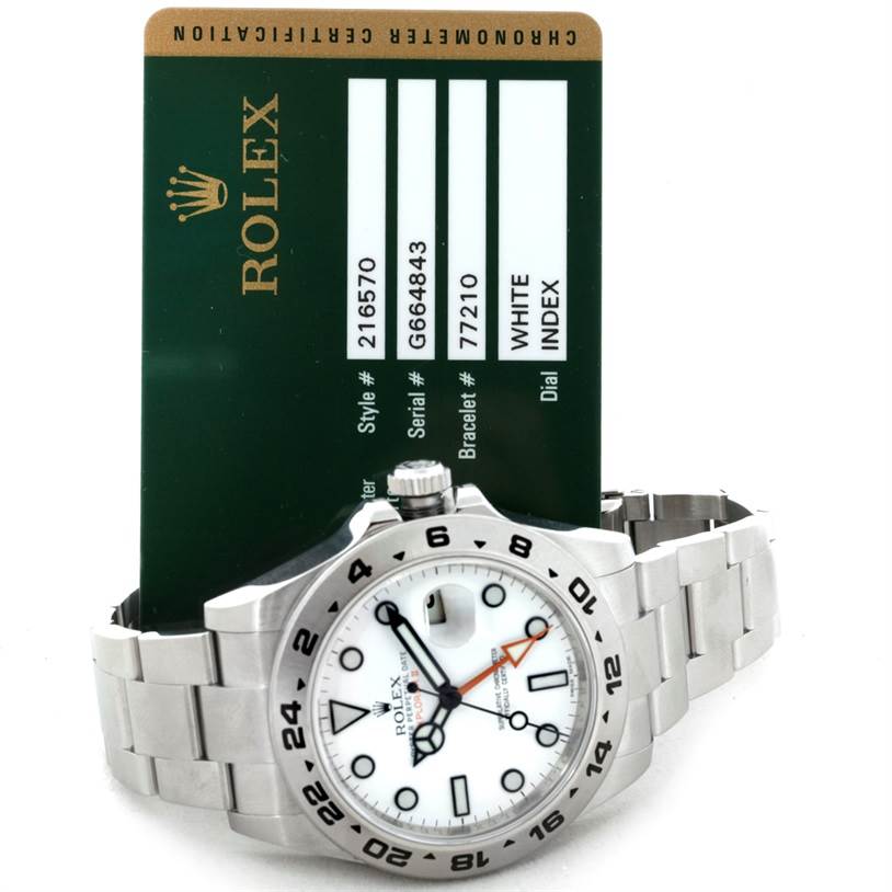 The image shows a Rolex Explorer 216570 Men
s Stainless Steel White Dial 216570 Men
s Stainless Steel White Dial watch with a white dial, presented at an angle revealing the face, bezel, and bracelet, along with its certification card.