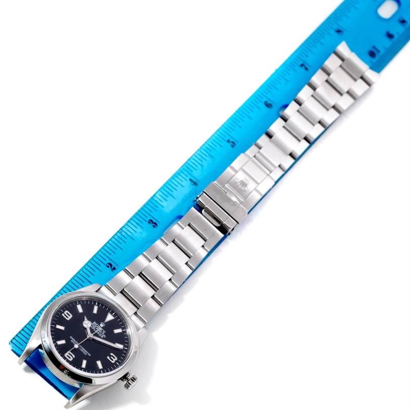 The image shows a Rolex Explorer 114270 Men's Stainless Steel Black Dial 114270 Men's Stainless Steel Black Dial watch laid flat next to a blue ruler, displaying the face, bezel, bracelet, and clasp.