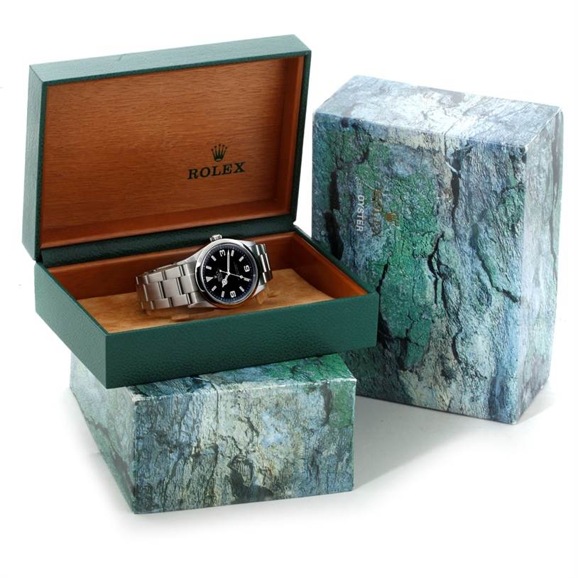 The Rolex Explorer 114270 Men's Stainless Steel Black Dial 114270 Men's Stainless Steel Black Dial watch is shown at an angle inside an open green and wood-finish Rolex box with a decorative outer box.