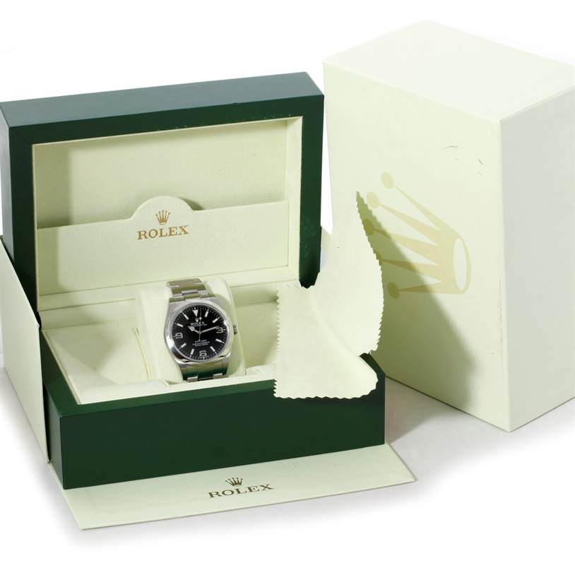 The Rolex Explorer 214270 Men's Stainless Steel Black Dial 214270 Men's Stainless Steel Black Dial watch is shown inside its green and cream-colored box, displaying the watch's face and part of the bracelet.