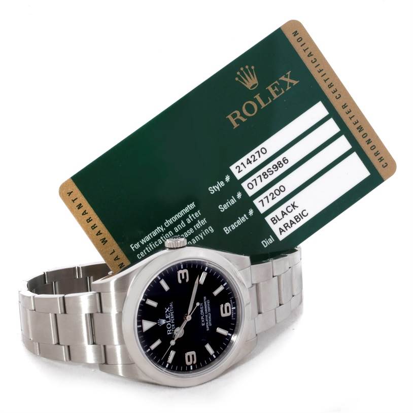 The image shows a Rolex Explorer 214270 Men's Stainless Steel Black Dial 214270 Men's Stainless Steel Black Dial watch laid flat with its certification card propped behind it.