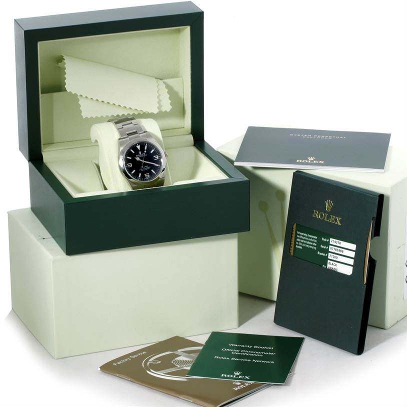 The image shows a Rolex Explorer 214270 Men's Stainless Steel Black Dial 214270 Men's Stainless Steel Black Dial watch in an open box with accompanying manuals and warranties around it.