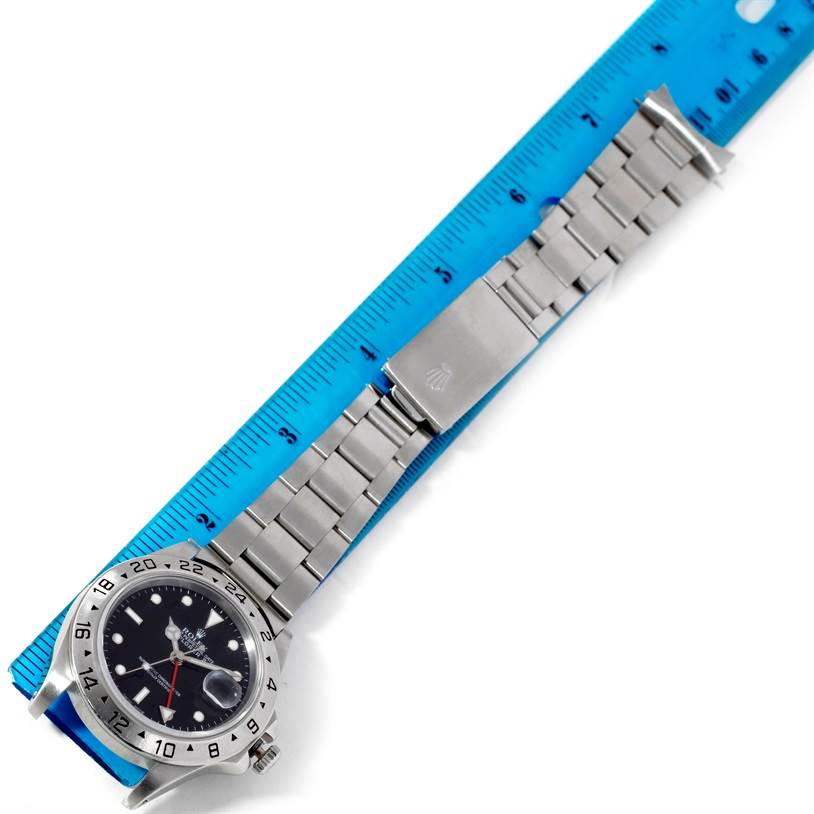 The Rolex Explorer 16570 Men's Stainless Steel Black Dial 16570 Men's Stainless Steel Black Dial watch is shown with its bracelet fully extended next to a blue ruler for scale.