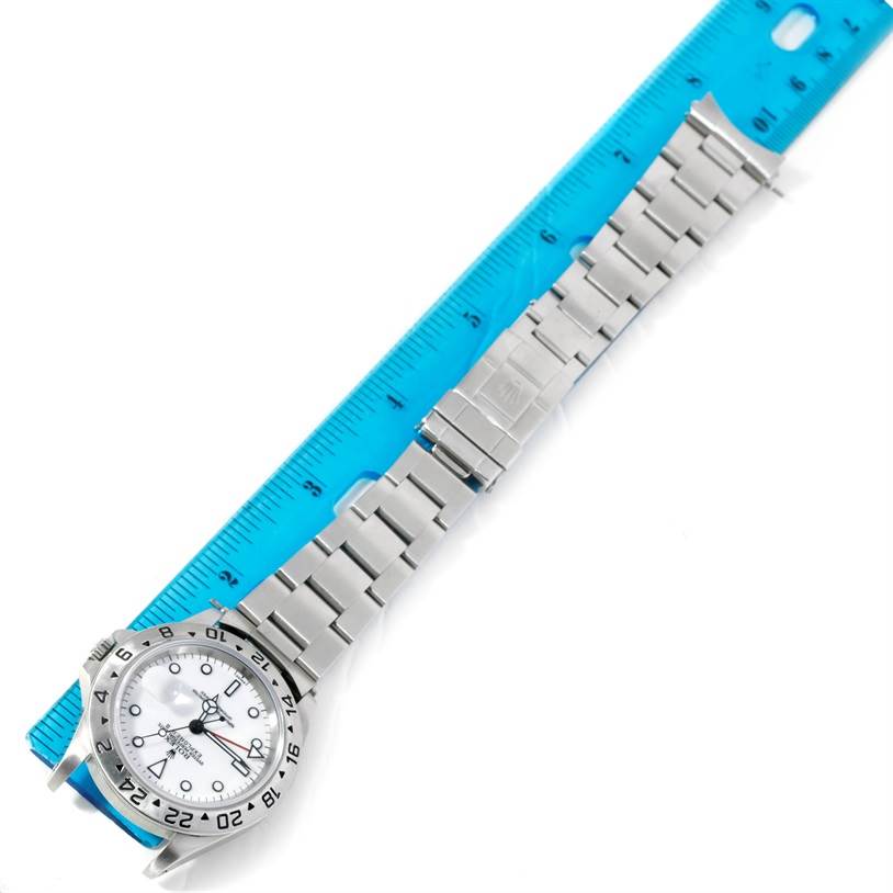 The image shows the Rolex Explorer 16570 Men's Stainless Steel White Dial 16570 Men's Stainless Steel White Dial watch placed alongside a blue ruler, displaying its face, bezel, and metal bracelet.