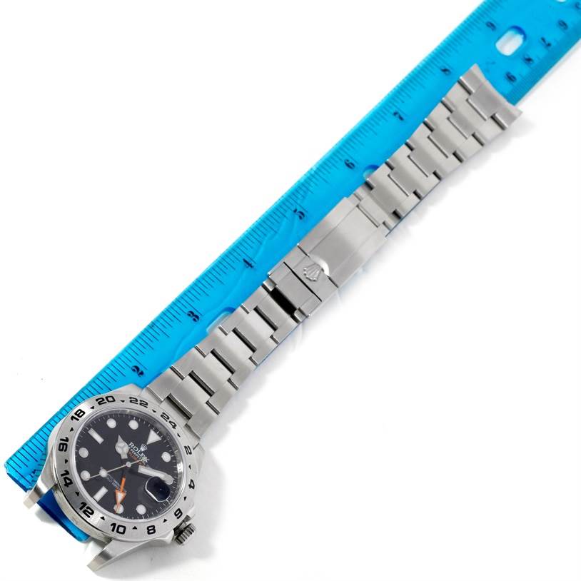 The image shows a Rolex Explorer 216570 Men's Stainless Steel Black Dial 216570 Men's Stainless Steel Black Dial model watch laid flat next to a ruler, displaying the face, bracelet, and clasp.