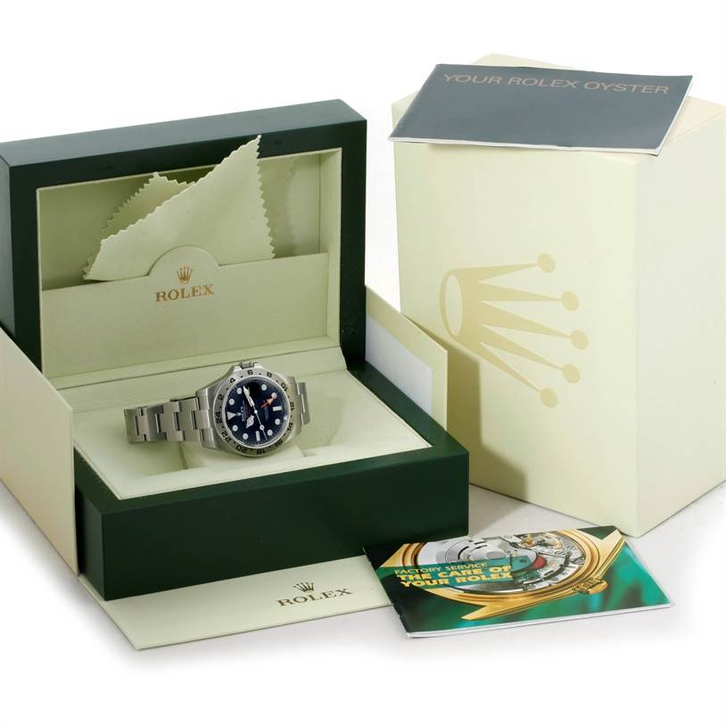 The Rolex Explorer 216570 Men's Stainless Steel Black Dial 216570 Men's Stainless Steel Black Dial watch is displayed inside an open green and cream Rolex box, with manuals and a cleaning cloth included.