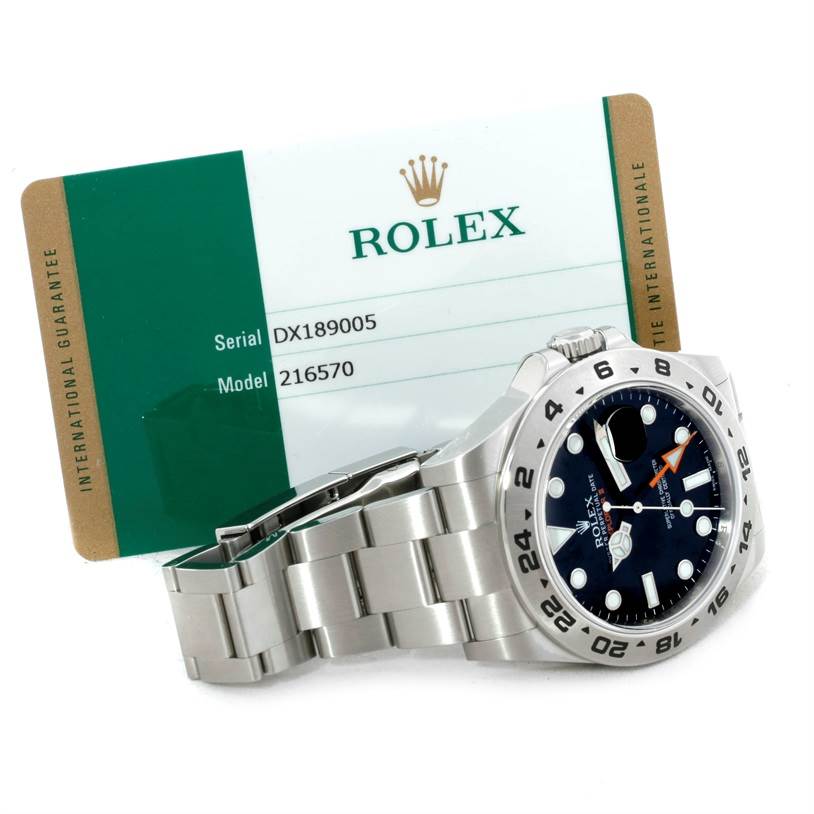 The image shows a side view of a Rolex Explorer 216570 Men
s Stainless Steel Black Dial 216570 Men
s Stainless Steel Black Dial model 216570 watch along with its international guarantee card.