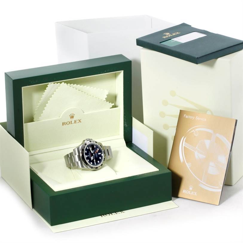 The image shows a Rolex Explorer 216570 Men
s Stainless Steel Black Dial 216570 Men
s Stainless Steel Black Dial watch in its open box along with a cleaning cloth and a factory service booklet.