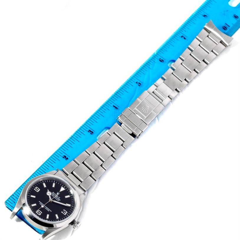 The Rolex Explorer 14270 Men's Stainless Steel Black Dial 14270 Men's Stainless Steel Black Dial watch is shown laid flat with its full bracelet and clasp visible, measured against a blue ruler.