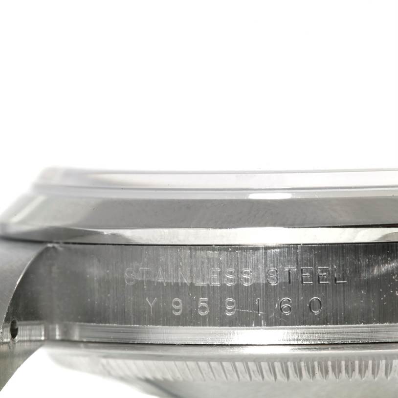 The image shows a close-up side angle of a Rolex Explorer 114270 Men's Stainless Steel Black Dial 114270 Men's Stainless Steel Black Dial watch, highlighting the stainless steel bezel and part of the case with engraved serial numbers.