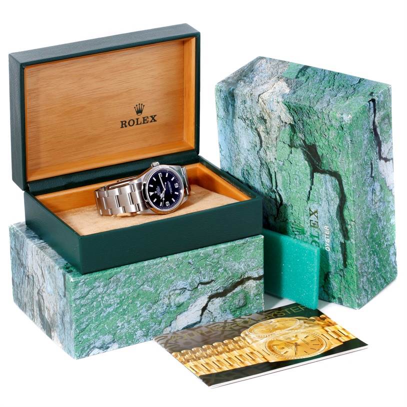 The image shows a Rolex Explorer 114270 Men's Stainless Steel Black Dial 114270 Men's Stainless Steel Black Dial watch in an open Rolex box with the exterior packaging and a brochure displayed.