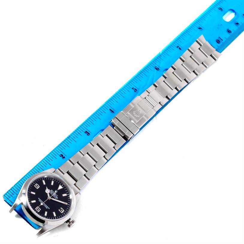 The Rolex Explorer 114270 Men
s Stainless Steel Black Dial 114270 Men
s Stainless Steel Black Dial watch is displayed flat with its face, bracelet, and clasp visible, alongside a ruler for scale.