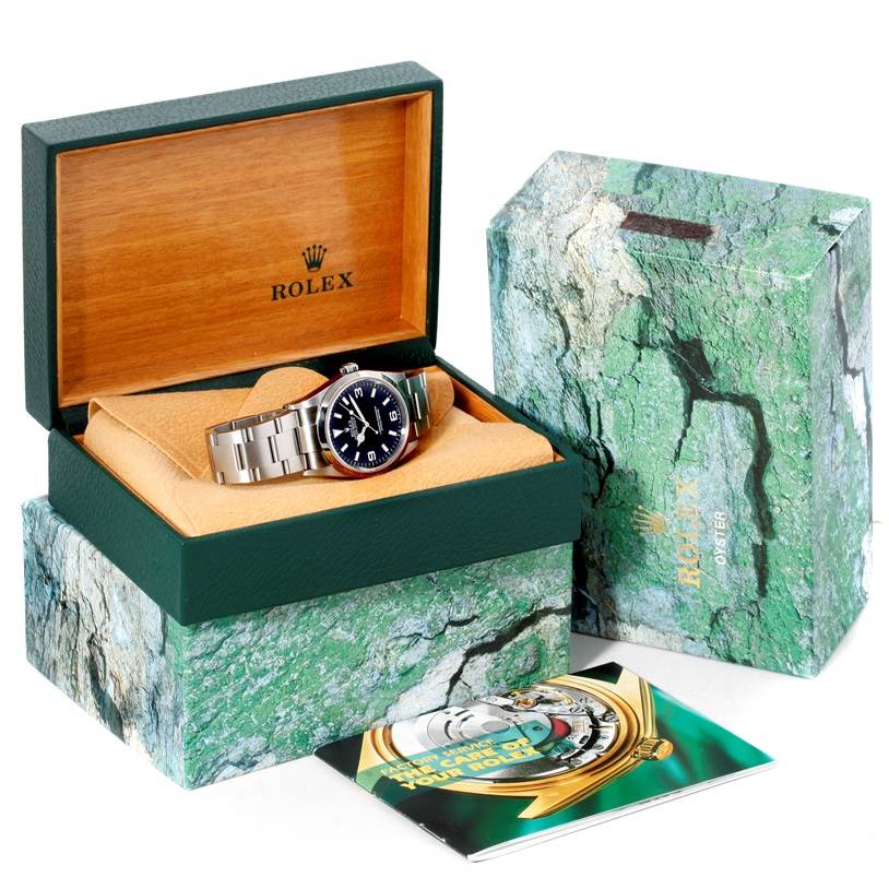The image shows a Rolex Explorer 114270 Men
s Stainless Steel Black Dial 114270 Men
s Stainless Steel Black Dial watch in its open box, with the box lid, packaging, and a booklet displayed.
