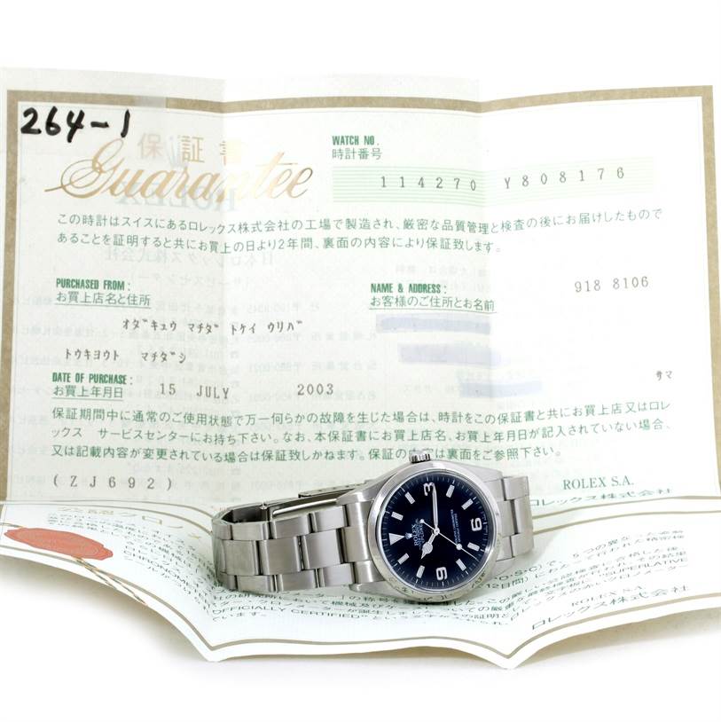The image shows a Rolex Explorer 114270 Men's Stainless Steel Black Dial 114270 Men's Stainless Steel Black Dial watch placed on a warranty certificate, photographed from a slightly elevated angle.