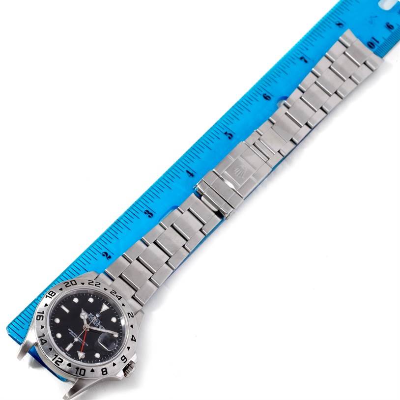 The image shows a top-down view of a Rolex Explorer 16570 Men's Stainless Steel Black Dial 16570 Men's Stainless Steel Black Dial watch with its stainless steel bracelet aligned next to a ruler.