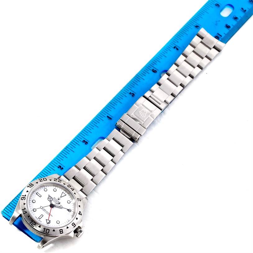The image shows the Rolex Explorer 16570 Men's Stainless Steel White Dial 16570 Men's Stainless Steel White Dial watch laid flat, with its full bracelet and clasp, adjacent to a blue ruler.