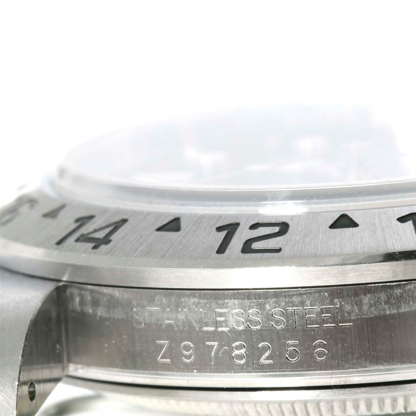 The image shows a side angle of the bezel and part of the case of a Rolex Explorer 16570 Men's Stainless Steel White Dial 16570 Men's Stainless Steel White Dial watch, highlighting the numerals and stainless steel engraving.