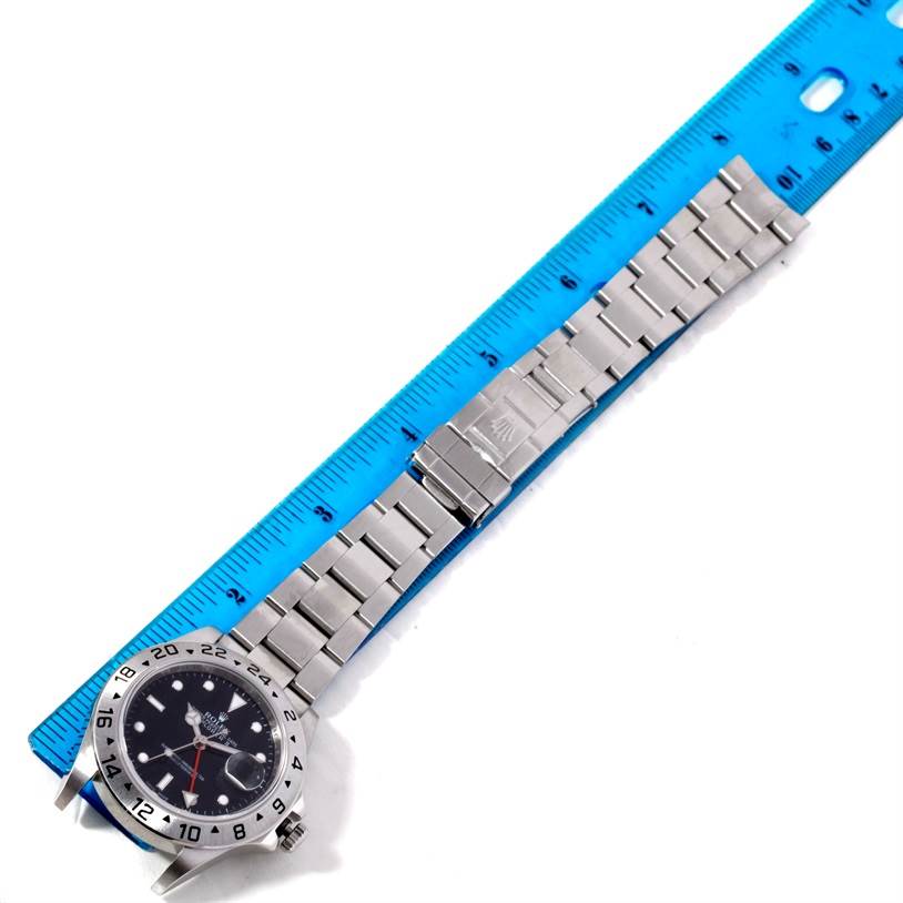 The image shows a Rolex Explorer 16570 Men's Stainless Steel Black Dial 16570 Men's Stainless Steel Black Dial model watch and its stainless steel bracelet, lying flat next to a blue ruler for scale.