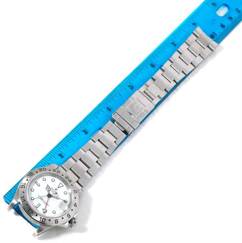 This image shows a Rolex Explorer 16570 Men's Stainless Steel White Dial 16570 Men's Stainless Steel White Dial watch laid flat next to a ruler, highlighting the bracelet and clasp.