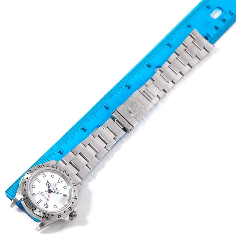 The image shows a top view of a Rolex Explorer 16570 Men's Stainless Steel White Dial 16570 Men's Stainless Steel White Dial watch, including the bracelet and clasp, alongside a blue ruler.