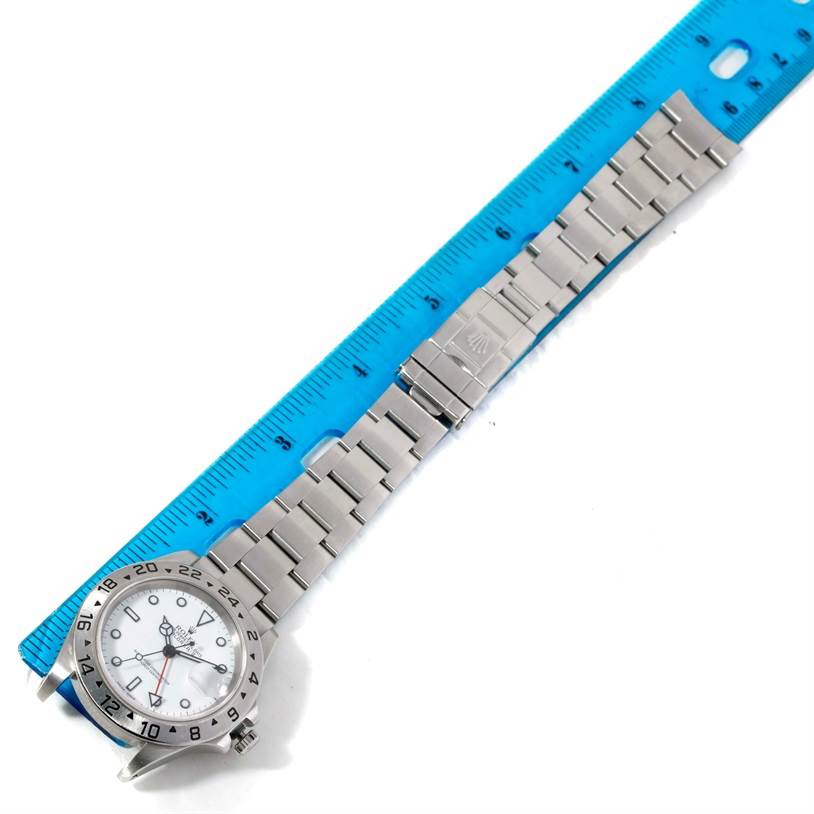 The image shows a Rolex Explorer 16570 Men's Stainless Steel White Dial 16570 Men's Stainless Steel White Dial watch laid flat next to a blue ruler, displaying the face, bracelet, and clasp.