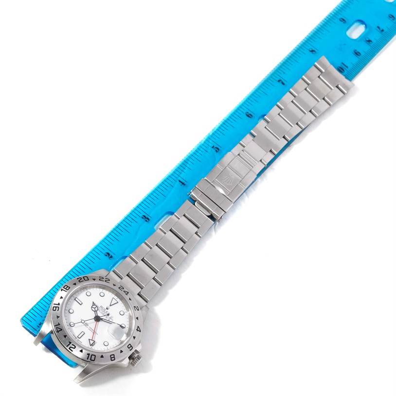 The Rolex Explorer 16570 Men's Stainless Steel White Dial 16570 Men's Stainless Steel White Dial watch is shown from the top, featuring its dial, bezel, and full metal bracelet alongside a blue ruler.