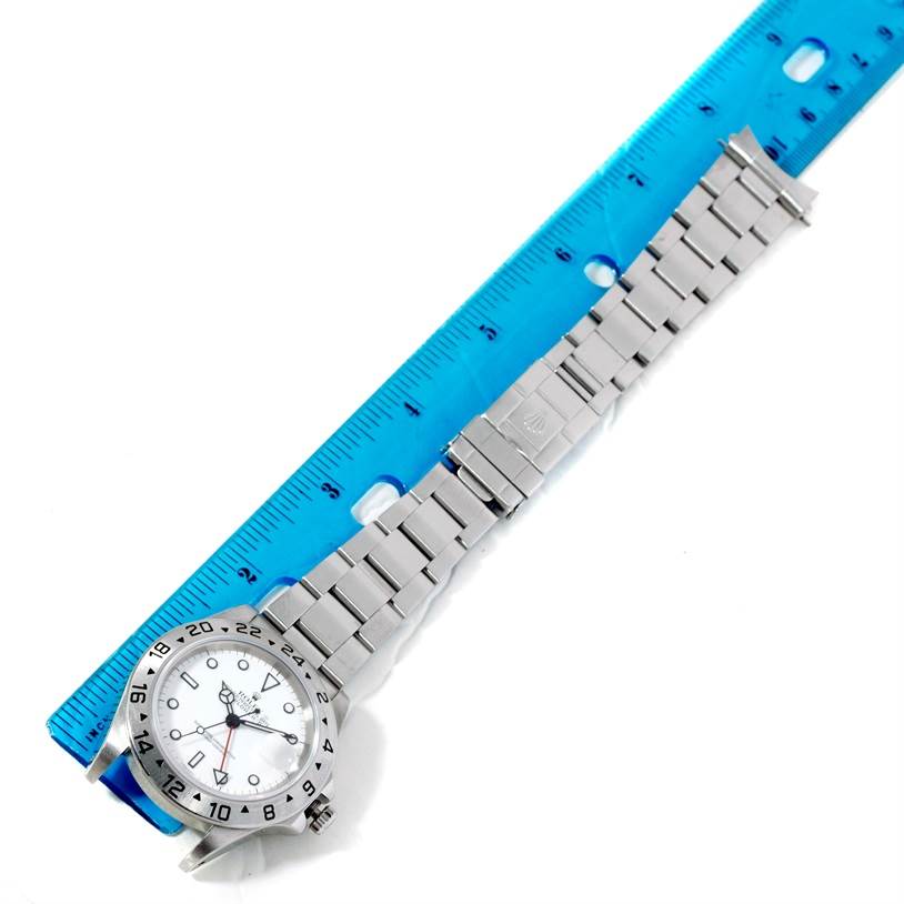 The image shows a Rolex Explorer 16570 Men's Stainless Steel White Dial 16570 Men's Stainless Steel White Dial watch laid flat, partially inside a blue ruler, highlighting the face and bracelet.