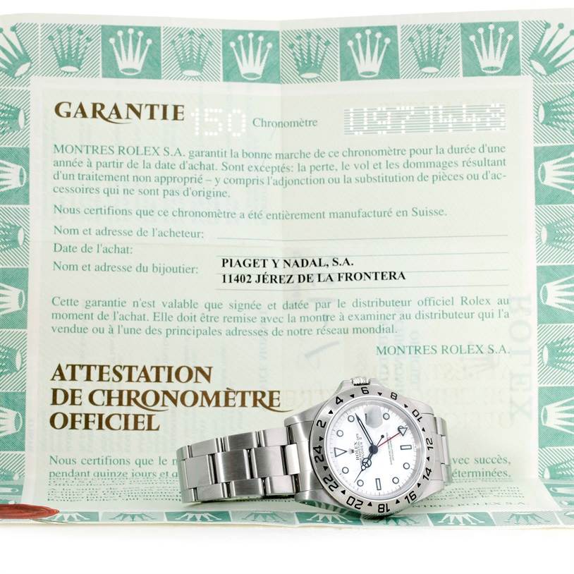 The Rolex Explorer 16570 Men's Stainless Steel White Dial 16570 Men's Stainless Steel White Dial watch is shown at an angle with the dial and bracelet visible, alongside its official warranty certificate.