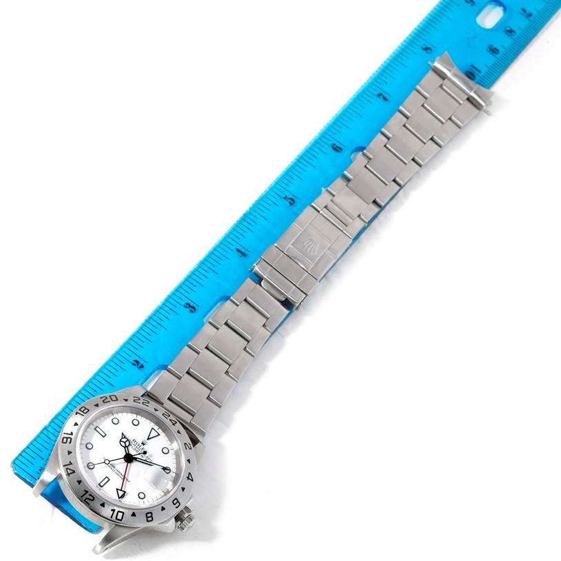 The Rolex Explorer 16570 Men
s Stainless Steel White Dial 16570 Men
s Stainless Steel White Dial watch is shown flat with the dial face and stainless steel bracelet visible beside a blue ruler.