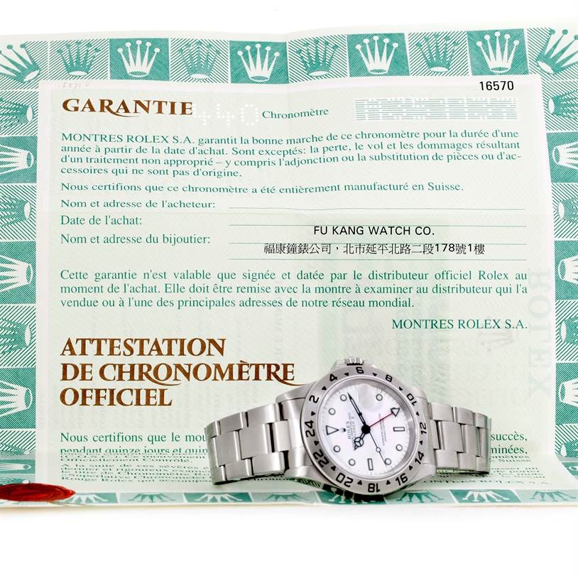 The image shows a Rolex Explorer 16570 Men
s Stainless Steel White Dial 16570 Men
s Stainless Steel White Dial watch laying flat on official warranty paperwork.