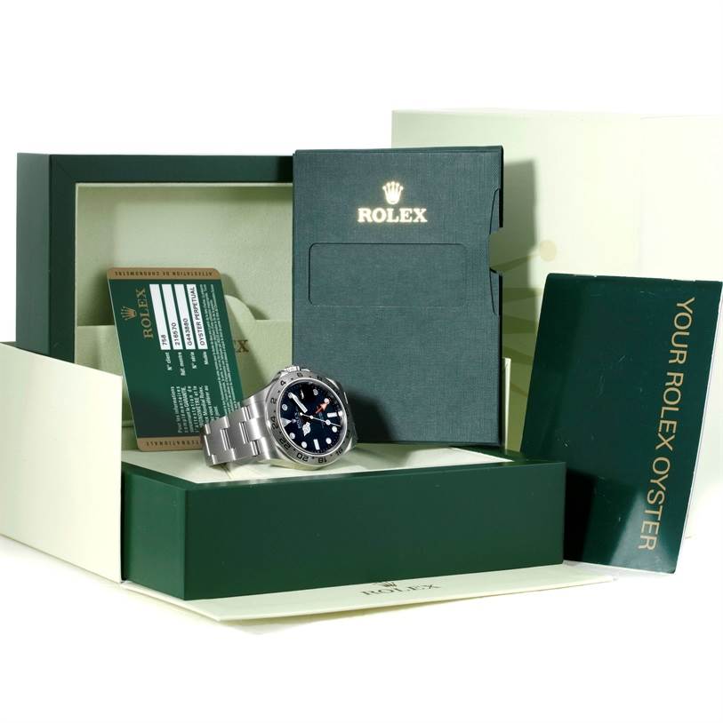 The image shows the Rolex Explorer 216570 Men's Stainless Steel Black Dial 216570 Men's Stainless Steel Black Dial watch, its box, warranty card, and booklet from a slightly elevated front angle.