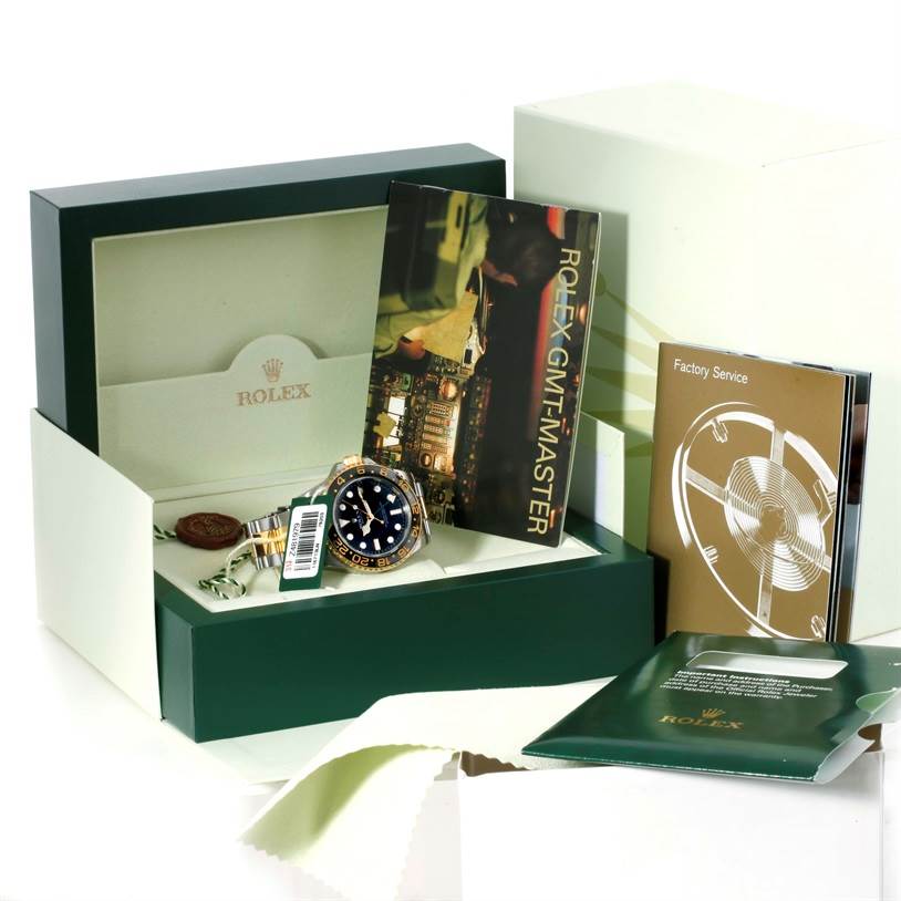 The image shows a Rolex GMT-Master 116713 Men's Stainless Steel Black Dial 116713 Men's Stainless Steel Black Dial watch at an angle inside its box with accompanying booklets and accessories.