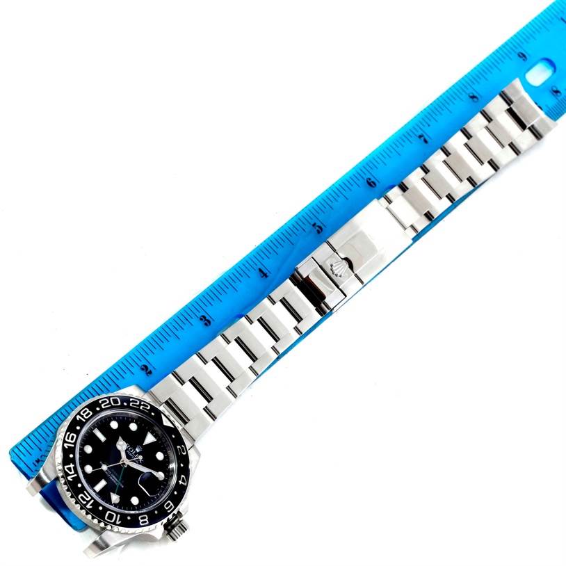 The image shows a top view of a Rolex GMT-Master 116710BKSO Men's Stainless Steel Black Dial 116710BKSO Men's Stainless Steel Black Dial watch with its bracelet next to a blue ruler for measurement.