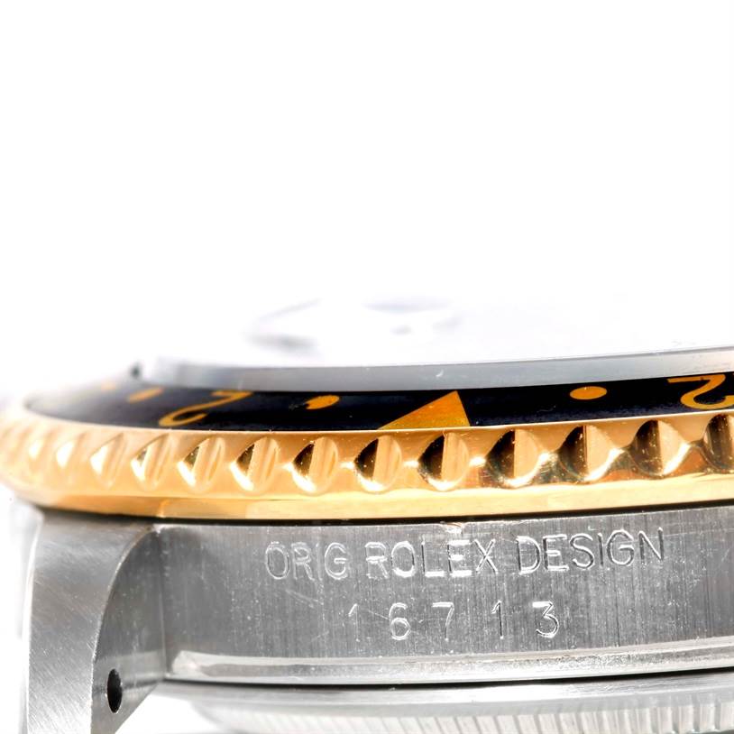 This close-up image of a Rolex GMT-Master 16713 Men's Stainless Steel Black Dial 16713 Men's Stainless Steel Black Dial watch showcases the bezel and part of the watch case, highlighting the engraved model number 16713.