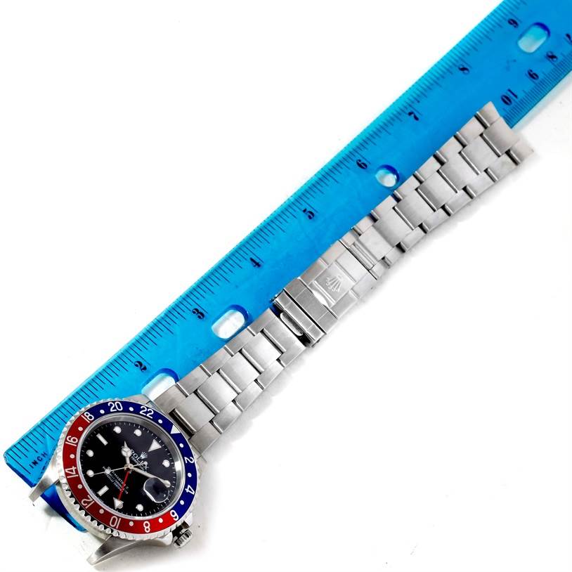 The image shows a Rolex GMT-Master 16710 Men's Stainless Steel Black Dial 16710 Men's Stainless Steel Black Dial watch laid flat with a ruler above it, displaying the watch face, bezel, and band.