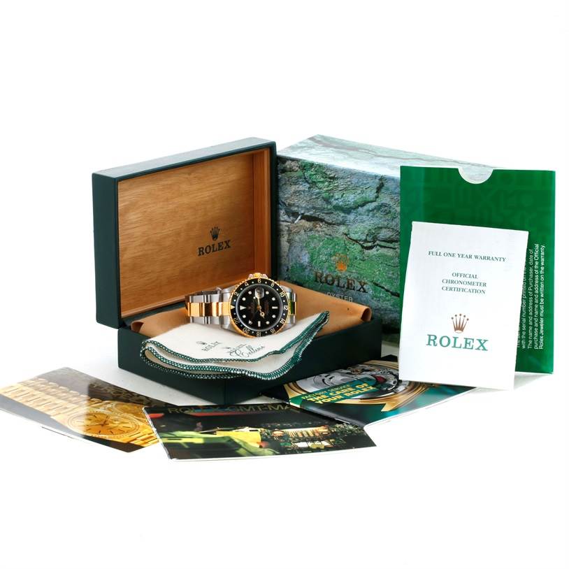 The image shows a Rolex GMT-Master 16713 Men
s Stainless Steel Black Dial 16713 Men
s Stainless Steel Black Dial watch in an open presentation box with accompanying documents and accessories.