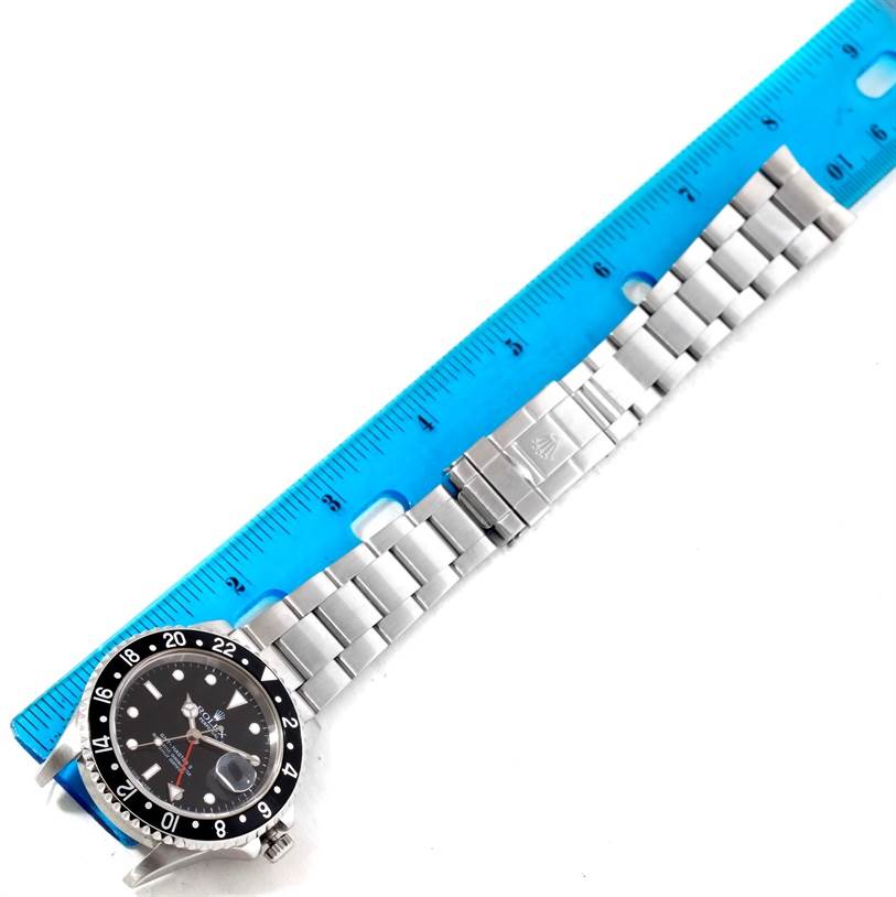 The image shows a Rolex GMT-Master 16710 Men's Stainless Steel Black Dial 16710 Men's Stainless Steel Black Dial watch positioned next to a ruler, displaying its bracelet, clasp, and watch face from a top-down angle.