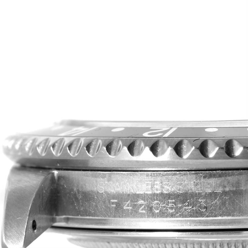 This close-up image of a Rolex GMT-Master 16710 Men's Stainless Steel Black Dial 16710 Men's Stainless Steel Black Dial watch shows the side view of the bezel, case, and part of the serial number engraving.