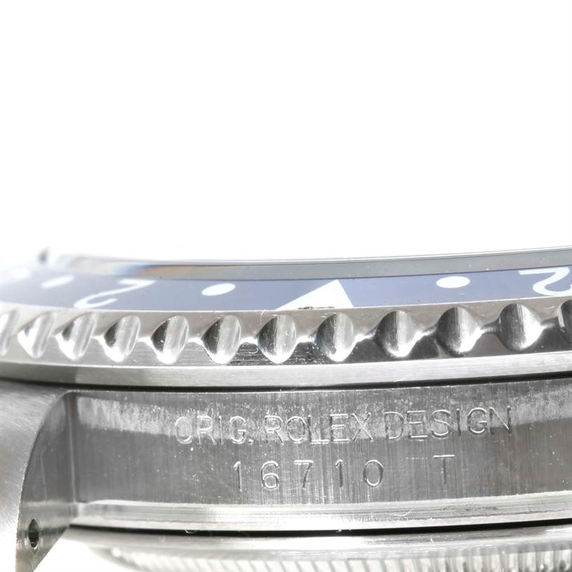 This close-up side angle of the Rolex GMT-Master 16710 Men's Stainless Steel Black Dial 16710 Men's Stainless Steel Black Dial watch shows the bezel and engraved model number, 16710 T.