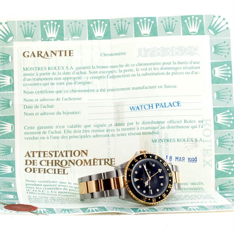 The image shows a Rolex GMT-Master 16713 Men's Stainless Steel Black Dial 16713 Men's Stainless Steel Black Dial watch placed at an angle on top of its warranty certificate.