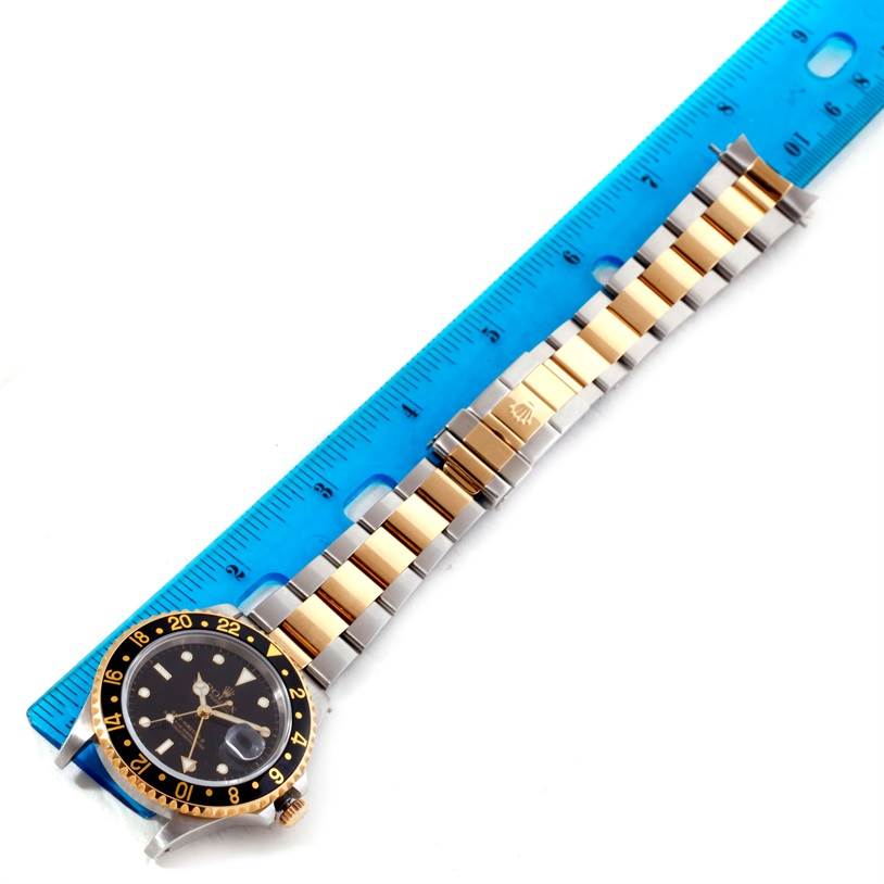 The image shows a Rolex GMT-Master 16713 Men's Stainless Steel Black Dial 16713 Men's Stainless Steel Black Dial watch laid flat next to a ruler, highlighting its bezel, dial, and bracelet.